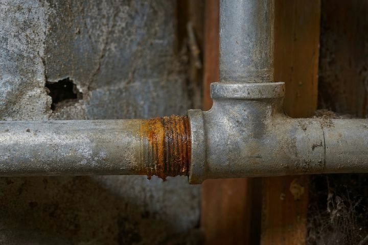 Close-up of galvanized steel pipe with rust weeping from a threaded joint