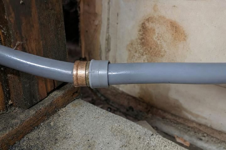 Close-up of gray polybutylene water pipe with a crimp ring fitting